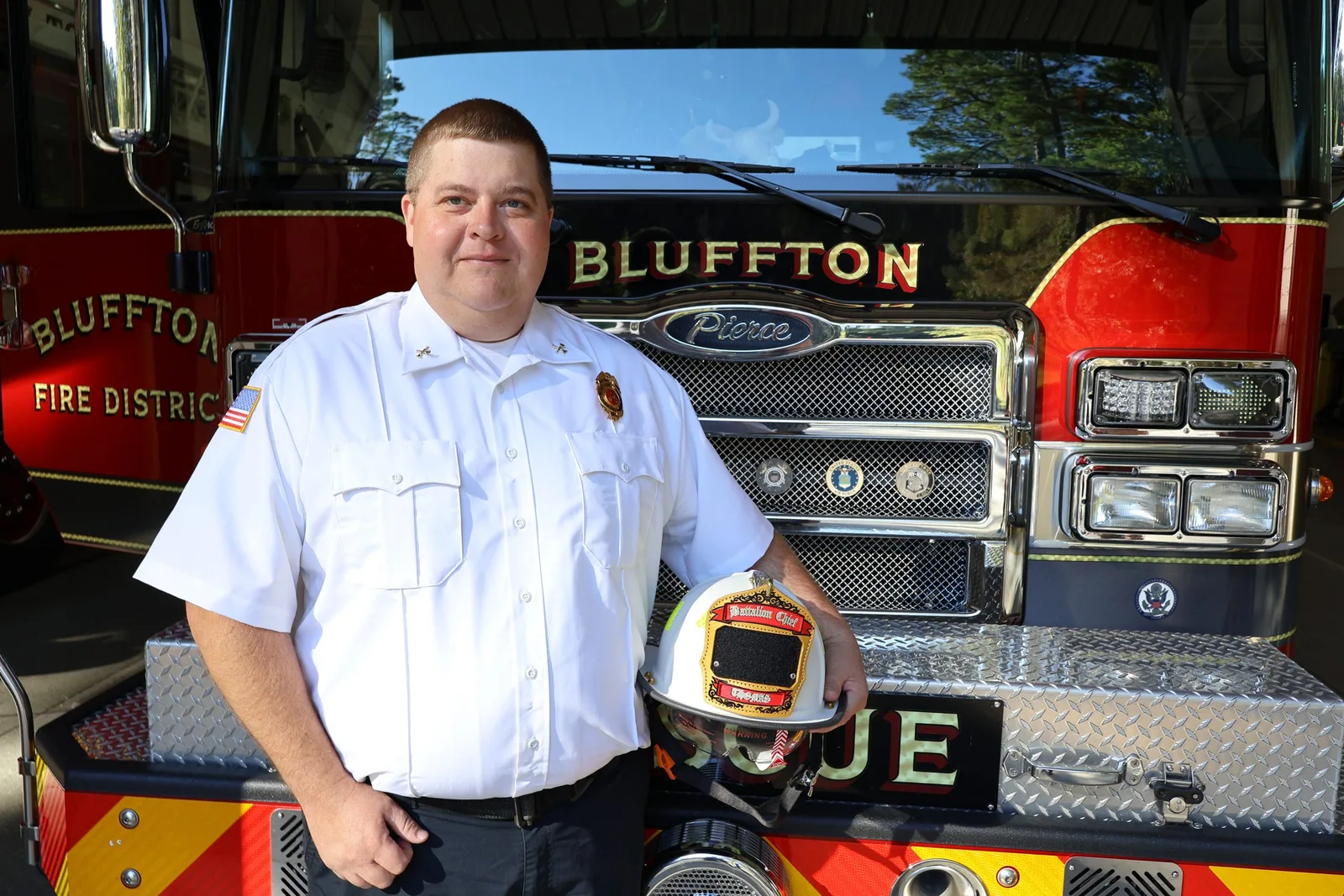 Battalion Chief James Thomas with his helmet in front of a Bluffton Township Fire District engine.