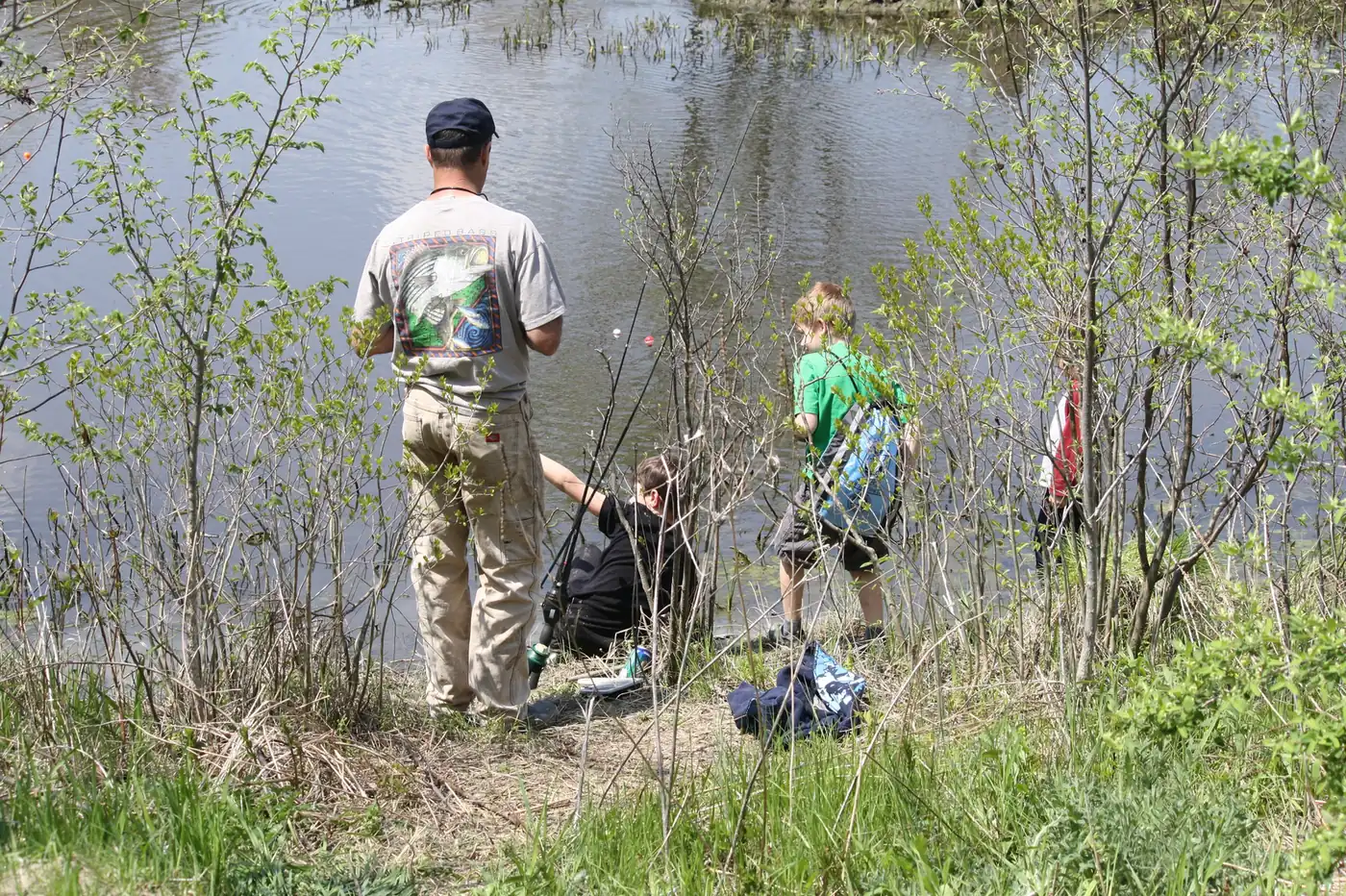 A father and son fish from a grassy bank at a U.S. Fish and Wildlife Service fishing derby in Hadley, Mass.