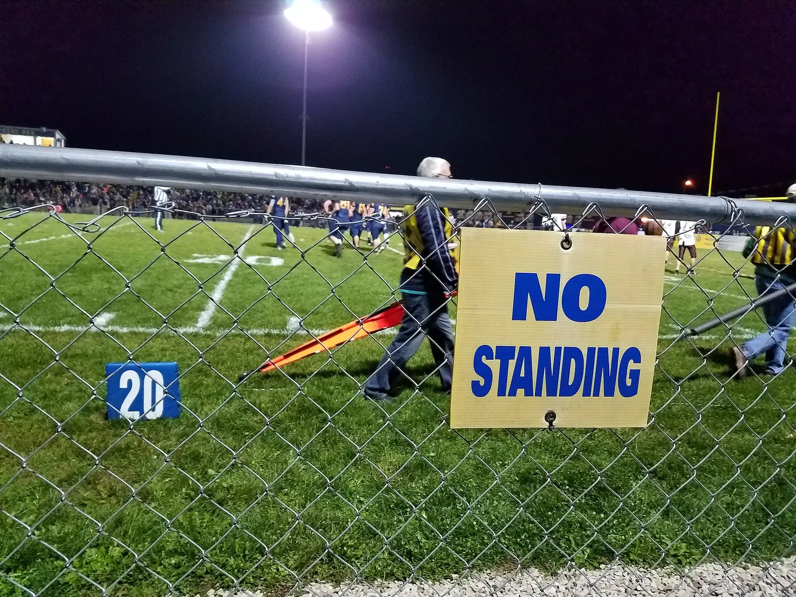 The chain crew works the sideline under the lights during a Friday night varsity football game at C. H. Jones Field in Wellston, Ohio.