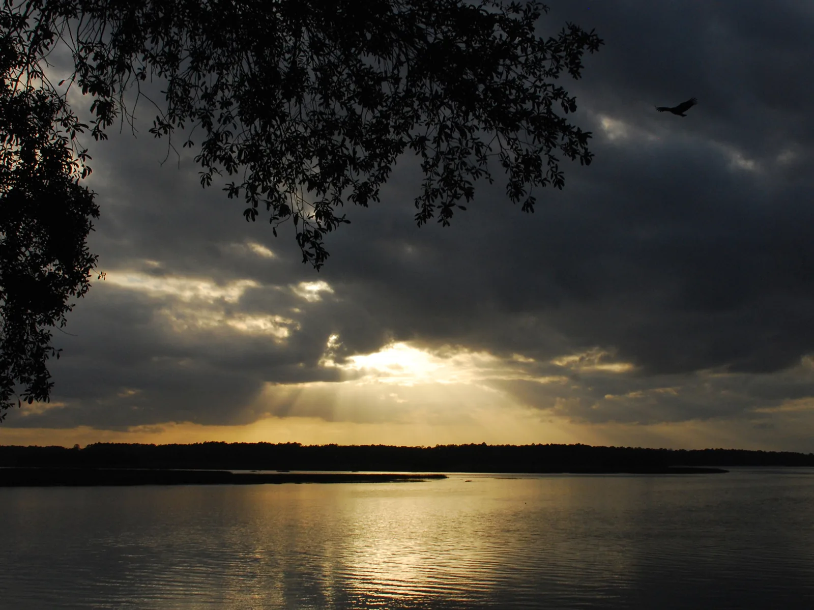 The sun breaks through clouds over the May River at sunset in Bluffton.