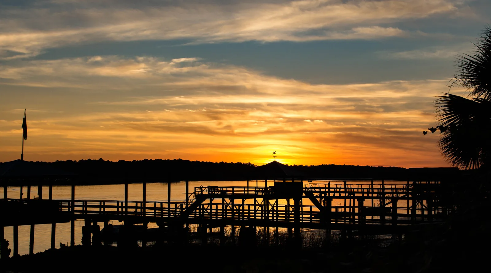 The sun sets over the May River behind the docks at Oyster Factory Park in Old Town Bluffton.