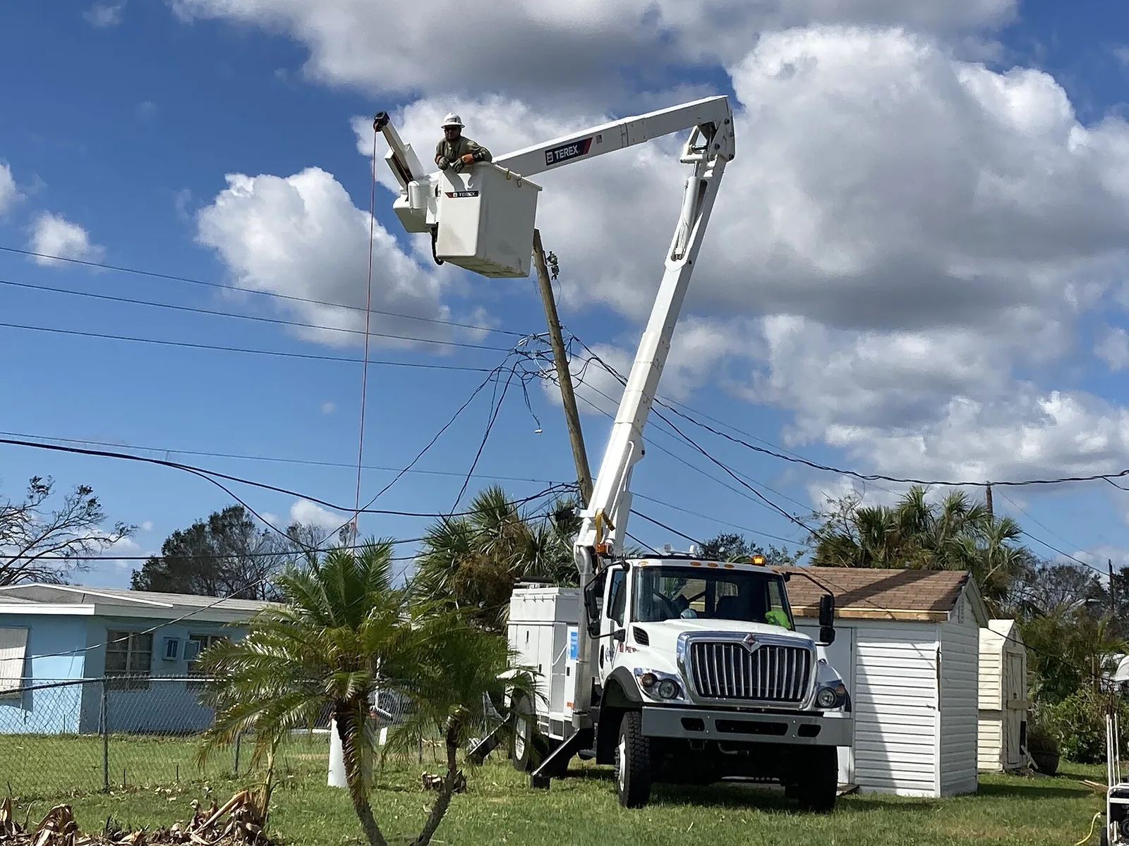 A utility lineman works from a bucket truck to restore power lines in Port Charlotte, Fla., after Hurricane Ian.