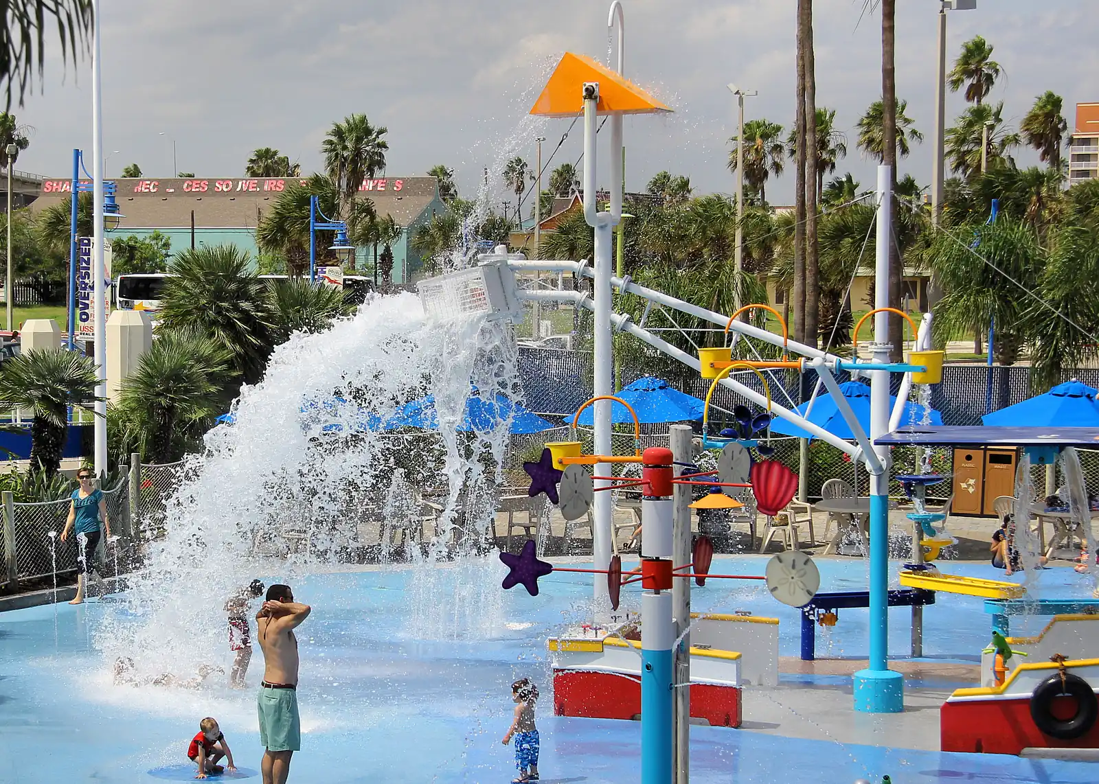 A giant bucket dumps water on children at a splash pad at the Texas State Aquarium in Corpus Christi, Texas.