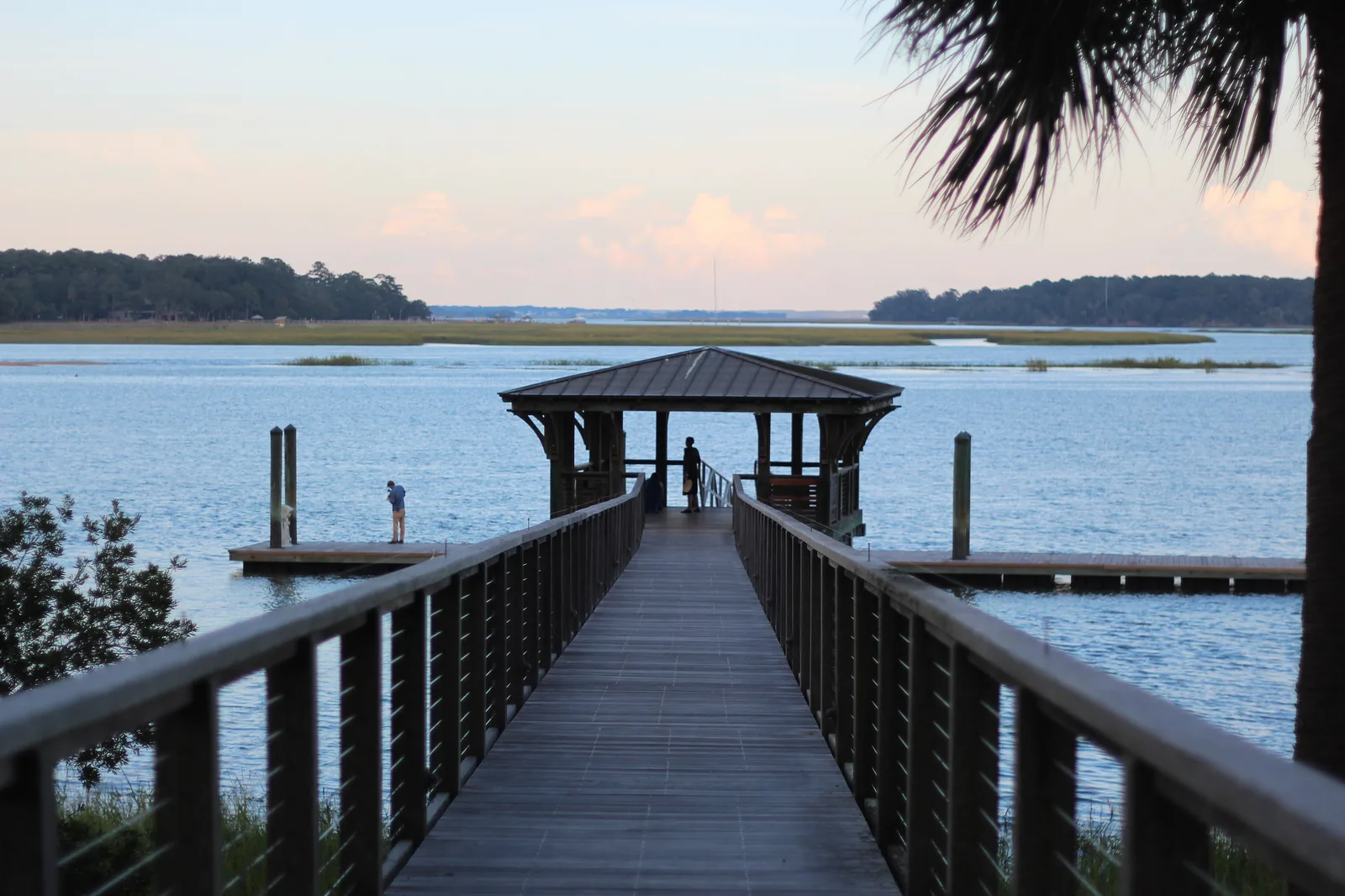 A boardwalk runs out to a covered dock on the May River at Palmetto Bluff in Bluffton at dusk.