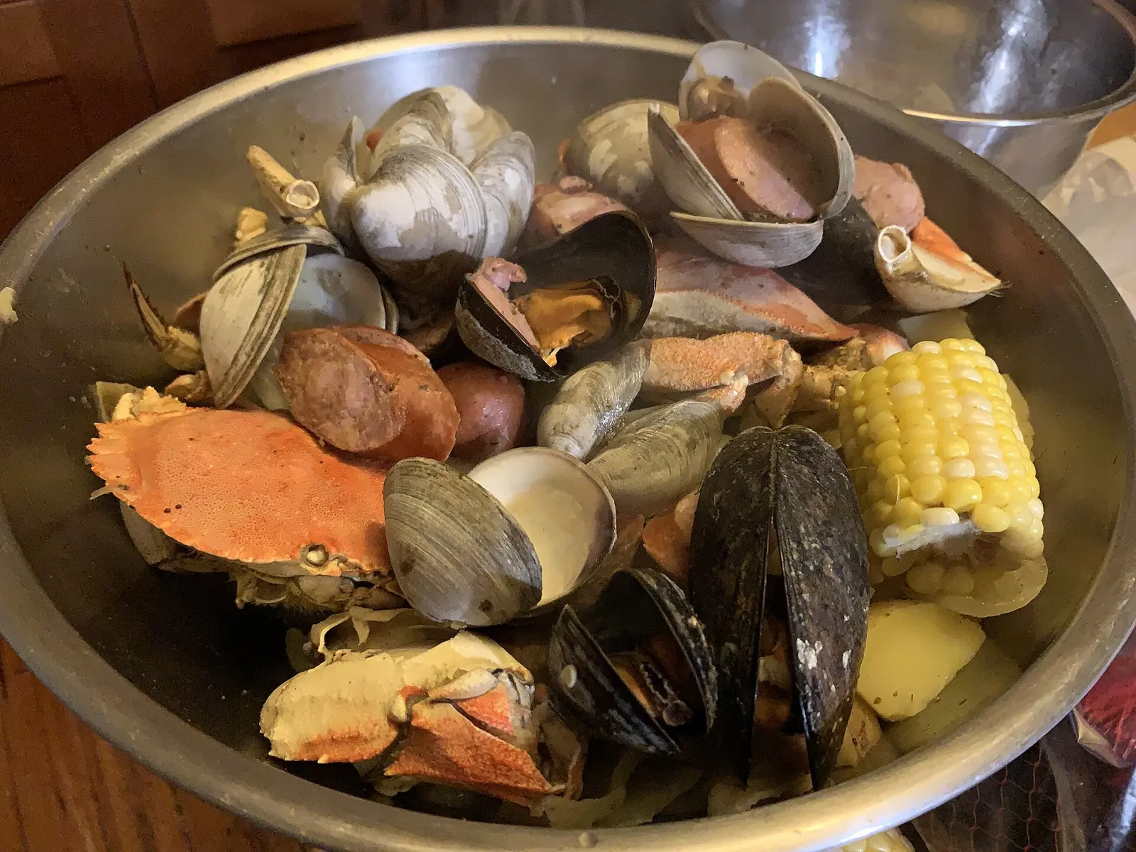 A seafood boil of crab, clams, mussels, sausage, potatoes and corn in a steel bowl. The photo was not taken at a Bluffton restaurant.